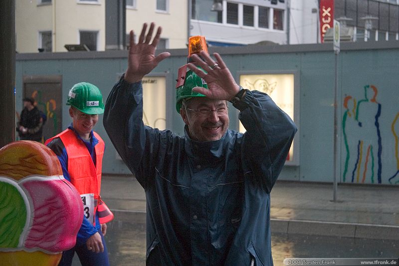 Teamleader Prof. Dr.-Ing. Jürgen Jensen mit der "Bauleiter-Rundumleuchte" auf dem Helm, Team "BaUnis - Das Team vom Bau!". Treffpunkt vor dem Lauf.\n1. Siegerländer AOK – Firmenlauf am 9. Juli 2004 in der Siegener Innenstadt über 5,5 km mit über 2200 gemeldeten Teilnehmern. Die Witterungsbedingungen mit teilweise strömenden Regen und zurückhaltenden Temperaturen waren leider nicht dem sommerlichen Datum angemessen, was der Lauffreude jedoch keinen Abbruch tat.