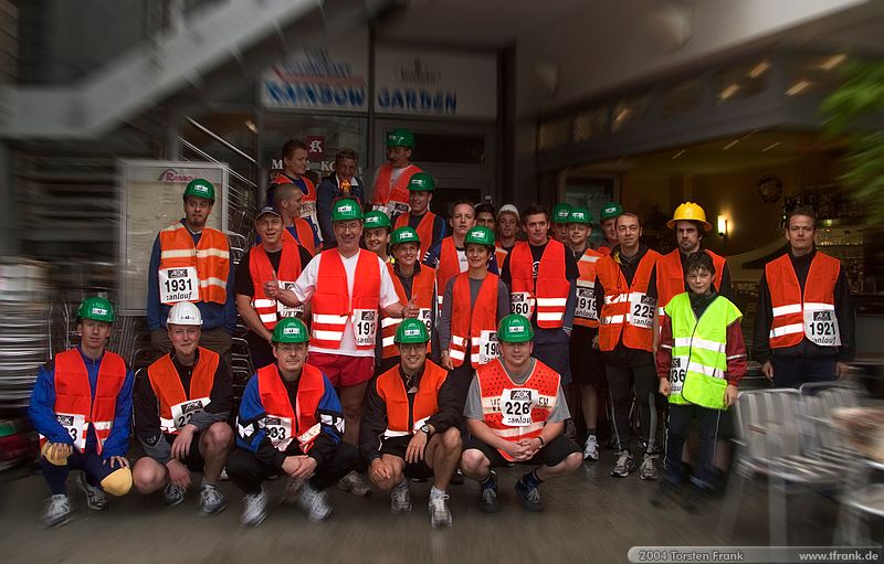 Gruppenfoto Team "BaUnis - Das Team vom Bau!" der Universität Siegen, Fachbereich Bauingenieurwesen. Treffpunkt vor dem Lauf auf dem Bahnhofsplatz vor dem WP-Gebäude.\n1. Siegerländer AOK – Firmenlauf am 9. Juli 2004 in der Siegener Innenstadt über 5,5 km mit über 2200 gemeldeten Teilnehmern. Die Witterungsbedingungen mit teilweise strömenden Regen und zurückhaltenden Temperaturen waren leider nicht dem sommerlichen Datum angemessen, was der Lauffreude jedoch keinen Abbruch tat.