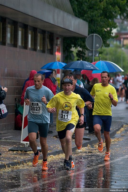 Weit vorn liegende Läufer am Ende der ersten Runde.\n1. Siegerländer AOK – Firmenlauf am 9. Juli 2004 in der Siegener Innenstadt über 5,5 km mit über 2200 gemeldeten Teilnehmern. Die Witterungsbedingungen mit teilweise strömenden Regen und zurückhaltenden Temperaturen waren leider nicht dem sommerlichen Datum angemessen, was der Lauffreude jedoch keinen Abbruch tat.