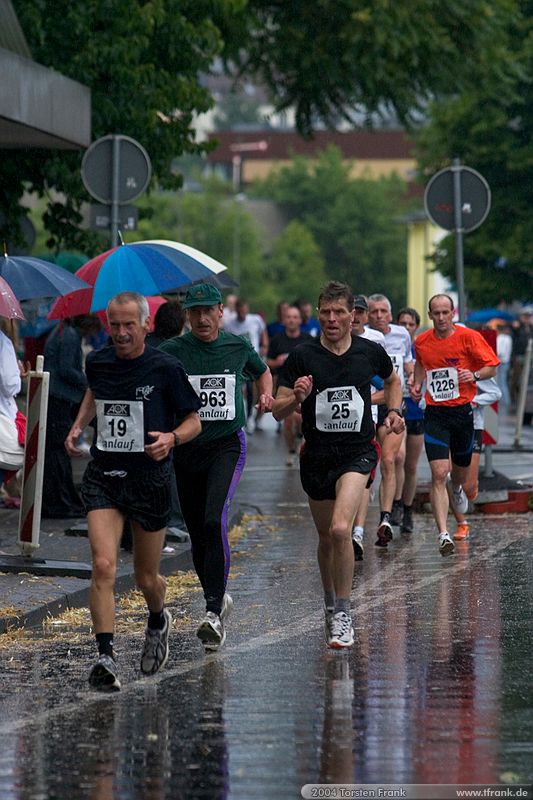 Weit vorn liegende Läufer am Ende der ersten Runde.\n1. Siegerländer AOK – Firmenlauf am 9. Juli 2004 in der Siegener Innenstadt über 5,5 km mit über 2200 gemeldeten Teilnehmern. Die Witterungsbedingungen mit teilweise strömenden Regen und zurückhaltenden Temperaturen waren leider nicht dem sommerlichen Datum angemessen, was der Lauffreude jedoch keinen Abbruch tat.