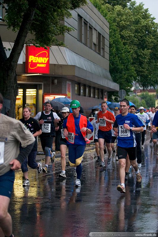 Christoph Mudersbach - am Ende der ersten Runde. Nach der zweiten wird er fitter aussehen ;-), Team "BaUnis - Das Team vom Bau!"\n1. Siegerländer AOK – Firmenlauf am 9. Juli 2004 in der Siegener Innenstadt über 5,5 km mit über 2200 gemeldeten Teilnehmern. Die Witterungsbedingungen mit teilweise strömenden Regen und zurückhaltenden Temperaturen waren leider nicht dem sommerlichen Datum angemessen, was der Lauffreude jedoch keinen Abbruch tat.