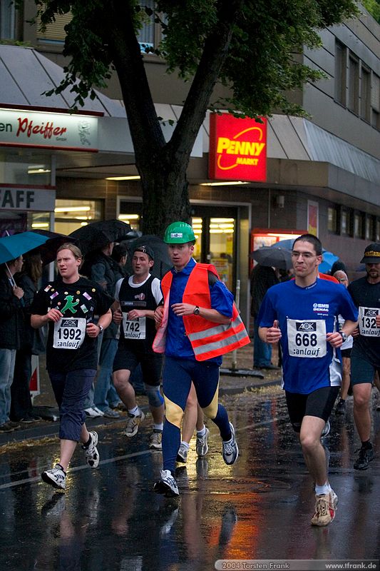 Christoph Mudersbach - am Ende der ersten Runde. Nach der zweiten wird er fitter aussehen ;-), Team "BaUnis - Das Team vom Bau!"\n1. Siegerländer AOK – Firmenlauf am 9. Juli 2004 in der Siegener Innenstadt über 5,5 km mit über 2200 gemeldeten Teilnehmern. Die Witterungsbedingungen mit teilweise strömenden Regen und zurückhaltenden Temperaturen waren leider nicht dem sommerlichen Datum angemessen, was der Lauffreude jedoch keinen Abbruch tat.